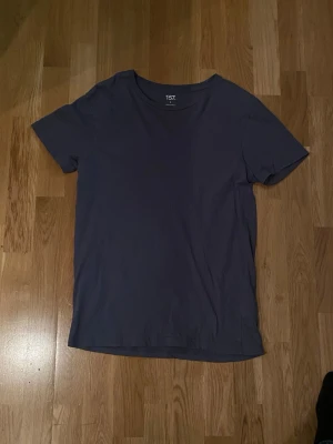 Mörkblå t-shirt från 157, storlek S - En enkel och stilren mörkblå t-shirt från 157 i storlek S. T-shirten är gjord av 100% bomull och har en klassisk rund hals samt korta ärmar. Perfekt för dig som gillar basic och bekväma plagg med clean look.