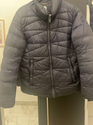 Svart pufferjacka från Colmar - Säljer en mörkblå pufferjacka från Colmar i storlek 50. Jackan har quiltad design, två sidofickor med dragkedja och hög krage. Materialet är polyester och jackan har en hel dragkedja framtill. Perfekt för kalla dagar och har en clean look. Finns lite hål men om du är intresserad så är det bara att skriva så skickar jag bilder på vart hålen är och hur de ser ut. Priset kan diskuteras.