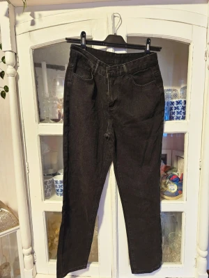 Svarta jeans med broderade fickor från SHEIN - Svarta jeans från SHEIN i storlek M med coola vita broderade flames på bakfickorna. Klassisk femficksmodell med dragkedja och knapp framtill. Materialet är bomull och polyester, och passformen är normal med raka ben.