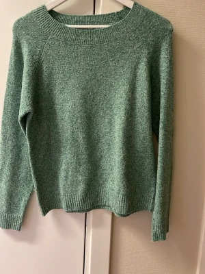 Grön stickad tröja från Vero Moda - Mysig grön stickad tröja från Vero Moda i storlek M. Tröjan har rund hals, ribbade muddar vid ärmslut och nederkant samt långärmad passform. Perfekt för att hålla sig varm under kyliga dagar och har en enkel, stilren look.