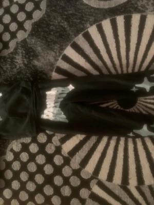 Svarta mjukisbyxor/hoodie - Svarta mjukisbyxor med coolt vitt tryck och stjärnliknande detaljer på benen. Byxorna har en avslappnad passform och är gjorda i mjukt material, perfekta för chill dagar. Resår i midjan för extra komfort.