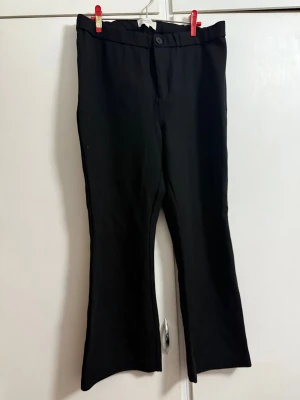 Svarta bootcut kostymbyxor Part Two - Svarta kostymbyxor från Part Two med bootcut-snitt och klassisk midja. Byxorna har knappstängning fram och två dekorativa bakfickor. Materialet är mjukt och har en snygg, stilren look som passar till många olika outfits.