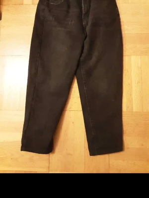 Svarta croppade jeansbyxor - Säljer ett par svarta jeansbyxor med croppad längd. Byxorna har klassisk femficksdesign och är tillverkade i ett slitstarkt jeanstyg. Passar dig som gillar en enkel och stilren look.