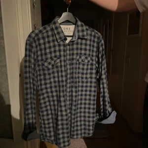 Blårutig skjorta från Jack & Jones - Säljer en blårutig skjorta från Jack & Jones Core med två bröstfickor och klassisk krage. Skjortan har långa ärmar och knappar framtill. Materialet är mjuk bomull som känns skönt mot huden. Perfekt för dig som gillar avslappnad stil med lite edge.