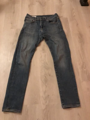 Blå jeans från J.Lindeberg 31/32 - Snygga blå jeans från J.Lindeberg i klassisk straight fit. Jeansen har fem fickor, orangea sömmar och är tillverkade i slitstarkt denim. Passar dig som gillar en tidlös look med lite tvättade detaljer. Perfekt för dig som vill ha ett par stilrena jeans i garderoben. Plus att dom säljes för 1000-1600 kronor nya så ganska bra pris. Bara att skriva vid frågor 