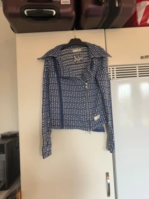 Blåvit stickad jacka från Odd Molly - Säljer en blåvit stickad kofta  från Odd Molly med rutigt mönster och cool sned dragkedja framtill. Jackan har stor krage, lång ärm och är croppad i modellen. Perfekt för dig som vill ha något unikt och snyggt i garderoben. Storlek 1 som enligt deras storleksguide motsvarar en S. Fint skick, men kan ha små tecken på användning. 