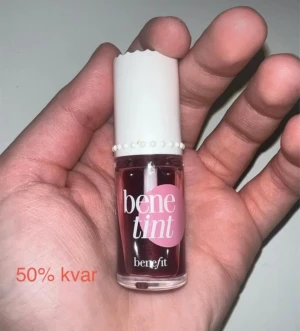 Benefit Benetint läpp- & kindfärg - Flytande tint från Benefit i färgen Benetint, perfekt för både läppar och kinder. Ger en naturlig rosig ton och kommer i en liten glasflaska med vit kork och söt detaljkant. Enkel att applicera med borste i locket.