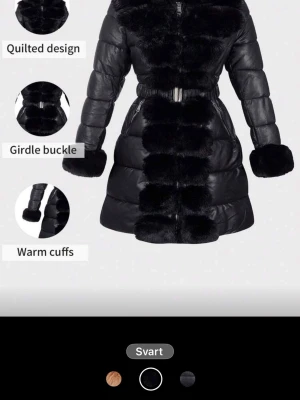 Svart quiltad pufferjacka med päls - Säljer en svart pufferjacka från Weird Poodle med quiltad design, pälsdetaljer längs krage, front och ärmslut. Jackan har ett brett bälte med metallspänne i midjan och dragkedjor vid fickorna. Perfekt för dig som vill ha en extra varm och snygg jacka i vinter.