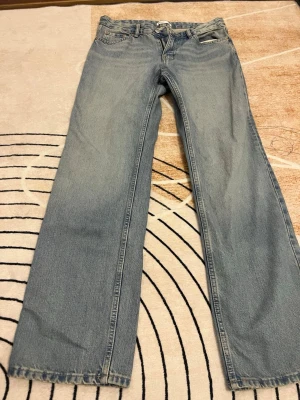 Jeans Gina tricot  - Säljer ett par klassiska jeans från Gina tricot ljusblåa tvätt med rak passform. Jeansen har fem fickor, knappgylf och är tillverkade i slitstarkt bomullsjeansmaterial. Perfekt för dig som gillar en tidlös och chill stil.