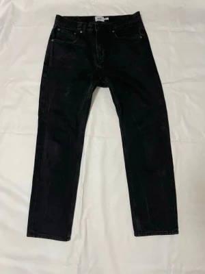 Svarta jeans från 157 New Classic - Svarta jeans från 157 New Classic med klassisk femficksdesign och raka ben. Jeansen har knapp och dragkedja i midjan samt diskreta sömmar. Materialet är jeans och färgen är helsvart, vilket gör dem enkla att matcha med olika stilar.