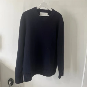  stickad tröja från A Day's March - En klassisk marinblå stickad tröja från A Day's March i storlek medium. Tröjan har rund halsringning, ribbade muddar och lång ärm. Perfekt för lager-på-lager och höstiga dagar.