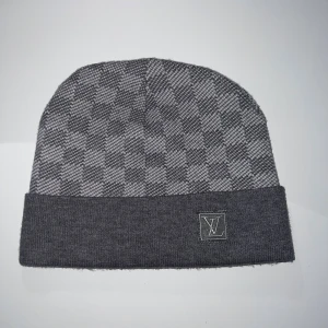 Louis Vuitton Mössa grå - Snygg grå mössa från Louis Vuitton med diskret rutmönster och klassisk LV-logga. Halsduken har en mjuk och lyxig känsla, perfekt för att lyfta din stil. Passar dig som gillar exklusiva accessoarer och vill sticka ut med något extra.