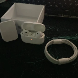AirPods Pro - Apple AirPods Pro i mycket fint skick, komplett med originalförpackning, laddningskabel och laddningsetui. Trådlösa hörlurar med aktiv brusreducering och silikontoppar för bästa passform. Inga synliga repor eller skador.