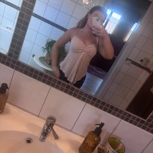 Ljusrosa linnetopp med knut framtill - Säljer en ljusrosa linnetopp med smala axelband och snygg knutdetalj framtill. Toppen har en lätt utsvängd passform och är perfekt för varma dagar. Mjuk och tunn i materialet, superenkel att matcha med jeans eller kjol.