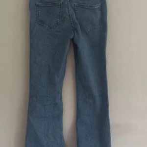 Blå bootcut jeans med normal passform - Snygga ljusblå jeans med klassisk bootcut och normal passform. Jeansen har fyra fickor, knapp och dragkedja framtill samt raka ben som blir vidare nedtill. Perfekta för dig som gillar retrovibbar och avslappnad stil. Stl 134/140