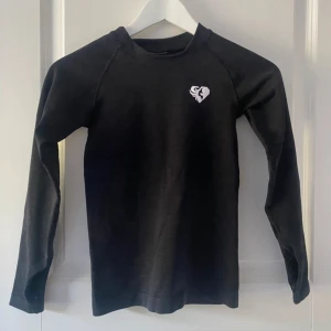 Svart långärmad tröja med tumhål - Använd 1 gång. Sitter jätte fint och tight, formar kroppen fint. Passar även XXS. Sälja inte längre på hemsidan. Köpt för €45.