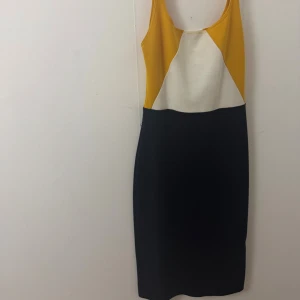 Midiklänning från Zara - Säljer en snygg midiklänning från Zara med smala axelband. Klänningen har färgblock i gult, vitt och svart och en liten slits bak. Den är figurnära och passar perfekt för dig som gillar stilrena men ändå färgstarka plagg.