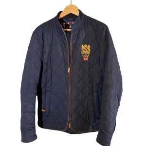 Morris quiltad jacka marinblå S - Quiltad marinblå jacka från Morris med guldbroderad logga och brittisk flagga på bröstet.  skick 8/10 och den kostar runt 2000kr