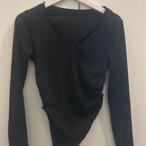 Svart och vit långärmad v-ringad topp - Två stilrena långärmade toppar i svart och vitt med djup v-ringning. Perfekta att matcha med jeans eller kjol. Tunn och mjuk känsla, figurnära passform och klassisk design. Säljes tillsammans eller separat.