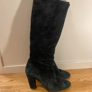 Svarta mockastövlar med klack - Snygga svarta stövlar i mocka med hög klack och rund tå. Stövlarna har dragkedja på insidan för enkel påtagning och en stilren, klassisk look som passar till många outfits.