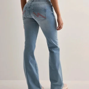 Ljusblå bootcut jeans med rosa detaljer - Snygga ljusblå jeans med bootcut passform och klassisk femficksdesign. Baktill finns coola rosa dekorsömmar på fickorna som ger extra attityd. Jeansen har normal midja och är tillverkade i mjukt denimtyg som sitter skönt hela dagen. Använda men fortfarande i väldigt bra skick utan defekter❤️❤️ Skriv till mig för egna bilder💕