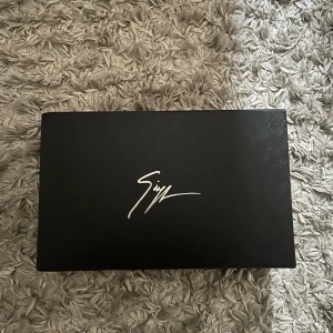 Svarta sneakers från Giuseppe Zanotti - Exklusiva svarta sneakers från Giuseppe Zanotti med croco-mönstrad skinnstruktur, guldfärgade dragkedjor och logga på plösen. Skorna har snörning, rund tå och platt sula. Lyxig känsla med snygga detaljer som sticker ut.