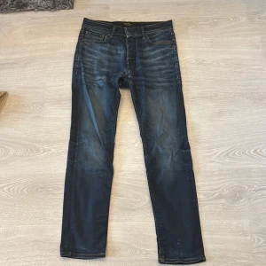 Mörkblå jeans från Jack & Jones 28/30 - Snygga mörkblå jeans från Jack & Jones i klassisk femficksmodell. Jeansen har raka ben, kontrastsömmar och lätt slitna detaljer framtill för en cool look. Tillverkade i mjukt jeansmaterial som sitter skönt hela dagen.