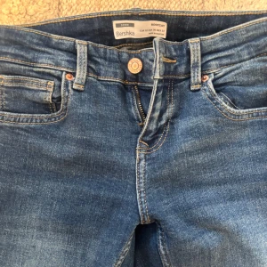 LOWWAIST Blå bootcut jeans från Bershka - NYSKICK Snygga blå jeans från Bershka i klassisk bootcut-modell. Jeansen har fem fickor, knapp och dragkedja framtill samt kontrastsömmar. Materialet är slitstarkt denim och passformen är normal med lätt utsvängda ben. Tveka inte på att höra av dig vid frågor eller intresse!