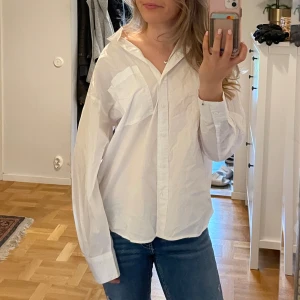 Vit oversized skjorta med knappar - Säljer en vit skjorta i oversized modell med klassisk krage och knappar framtill. Skjortan har långa ärmar och en bröstficka. Perfekt för en chill och stilren look, lätt att matcha med jeans eller kjol. 
