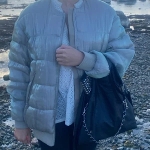 Pufferjacka med dragkedja - Säljer en beige/silvrig pufferjacka med glansig grön-ish finish och ribbade muddar. Står ingen storlek men gissar M💕