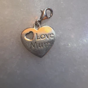 Thomas Sabo hjärtberlock Love Mum - Söt hjärtformad berlock från Thomas Sabo i silverfärg med texten 'Love Mum' och ett litet utskuret hjärta. Perfekt att fästa på armband eller halsband. Kommer med karbinhake för enkel fastsättning.