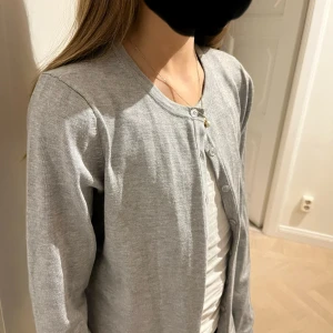 Grå kofta från Saint Tropez, S - En jättefin, grå kofta från Saint Tropez i storlek S. Koftan har rund halsringning, knäppning framtill med knappar och är långärmad. Väldigt bra kvalité, skriv gärna för fler bilder eller funderingar 