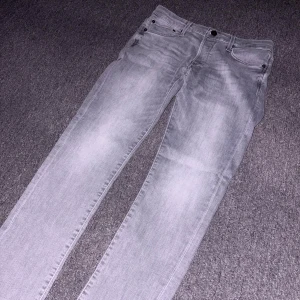Slim Glenn grå jeans, storlek 31/30 - Snygga grå jeans från Jack and Jones i modellen Slim Glenn i en slim passform. Jeansen har klassisk femficksdesign, knapp och dragkedja i gylfen samt diskreta slitningar för en cool look. Perfekta för dig som gillar stilrena och moderna jeans.