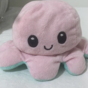 Vändbar bläckfisk plushie - Söt vändbar bläckfisk plushie med två ansikten: glad rosa och arg turkos. Mjuk och gosig, perfekt som present eller dekoration. Inga synliga defekter eller slitage, ser ut att vara i mycket gott skick.