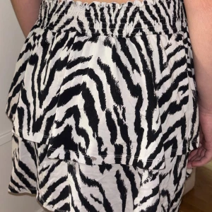 Zebramönstrade kjol från Gina Tricot - Säljer kjol från Gina Tricot. Svartvita med elastisk midja och tillverkade i mjuk bomull. Kjolen har en avslappnad passform och dubbla lager tyg för en cool look.