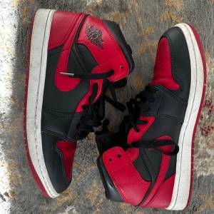 Nike Air Jordan 1 Mid Banned - Säljer ett par Nike Air Jordan 1 Mid Banned i klassisk röd och svart färg. Skorna har snyggt läder, röd swoosh och ikonisk Air Jordan-logga på sidan. Perfekta för dig som vill sticka ut med en tidlös sneaker. Köptes på restocks.net för 2 år sedan för 2500 kr, pris kan diskuteras