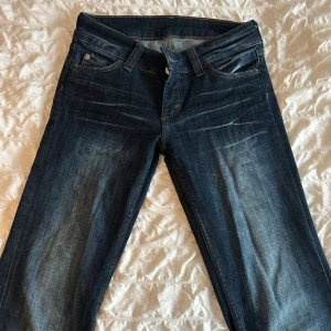 Booty Bei mörkblå jeans med raka ben - Mörkblå jeans från Booty Bei med raka ben och klassisk femficksdesign. Jeansen har snygga slitningar framtill och kontrastsömmar. Tillverkade i bomull med en skön passform som sitter snyggt på kroppen.