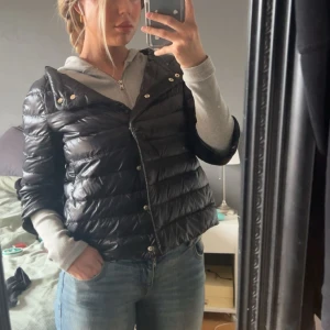 Svart pufferjacka från Herno Iconico - Säljer en svart, glansig pufferjacka från Herno Iconico. Jackan har horisontella sömmar, knappar framtill och en klassisk krage. Köpt för 5 000kr inga märken eller slitage alls. Pris kan diskuteras