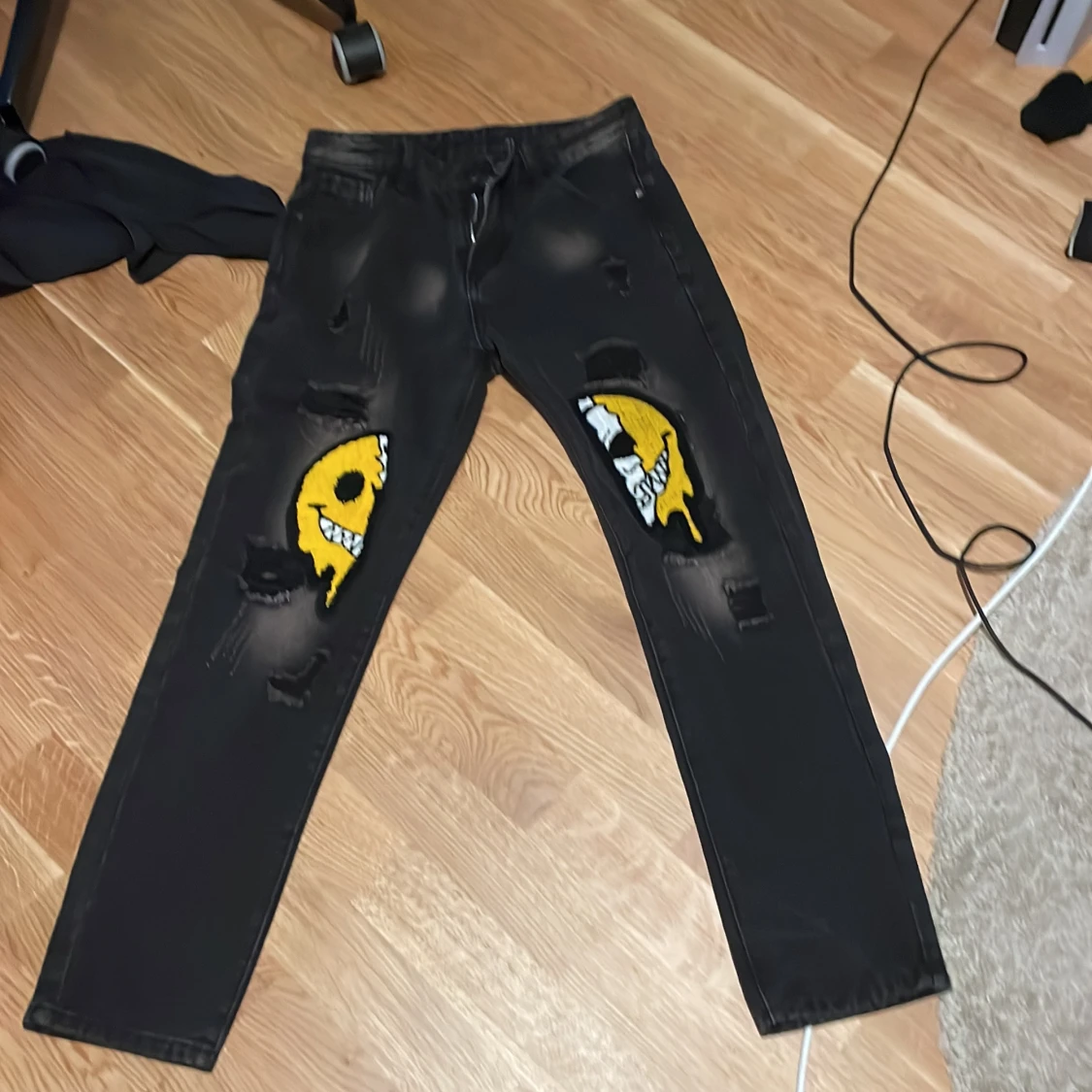 Svarta jeans med smiley-patch och slitningar
