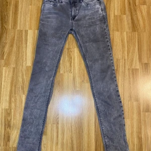 Replay grå skinny jeans - Snygga grå skinny jeans från Replay med slitna detaljer och klassiska bakfickor med broderad design. Jeansen har en smal passform och är tillverkade i stretchigt denim för extra komfort. Perfekta för dig som gillar en modern och stilren look.