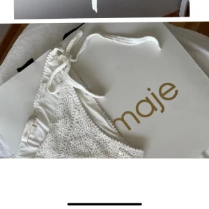 Vit virkad bikini från Maje - Superfin vit bikini från Maje med virkad look och knyt i sidorna och nacken. Bikinin har en trendig och bohemisk känsla, perfekt för stranden. Snygga detaljer och mjukt material som känns bekvämt mot huden.