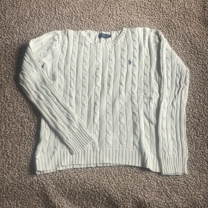 Vit kabelstickad tröja Polo Ralph Lauren - Vit kabelstickad tröja från Polo Ralph Lauren med klassisk blå broderad logga på bröstet. Tröjan har rund halsringning, ribbade muddar och är långärmad. Perfekt för lager-på-lager och snygg till jeans. STORLEK XS/S den har KRYMPT i tvätten! har du frågor är det bara att hojta till😆🙌. MVH SWISSWEAR 🇨🇭🍾🏔️