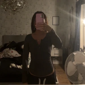 Mörkgrå långärmad tröja med knappar - Säljer en mörkgrå långärmad tröja med v-ringning och knappar framtill. Tröjan har en slim passform och är perfekt för dig som gillar en enkel men snygg stil. Skön och stretchig, passar till allt.