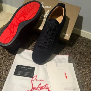 Blåa sneakers från Christian Louboutin - Snygga blåa sneakers från Christian Louboutin med klassisk röd sula och diskret broderad logga på hälen. Skorna har rund tå, platt sula och snörning. Utsidan är i mjuk mocka och insidan i ljust skinn, vilket ger en lyxig känsla. Perfekt för dig som gillar exklusiva detaljer.