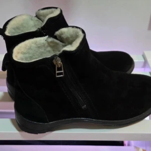 NYA! Varma Mockakängor med Ullfoder & Dragkedjor - Strl 38 (Passar 39/40) - Säljer ett par helt nya och oanvända ankelhöga kängor i svart mockaimitation. Kängorna har ett tjockt och varmt ull- eller fårskinnsfoder inuti, vilket gör dem perfekta för vinter och kyla. De har en bekväm design med en dragkedja på varje sida, vilket gör dem enkla att ta på och av. Sulan är stadig och ger bra grepp.  OBSERVERA STORLEKEN:  Även om det står storlek 38 på kängorna, är min bedömning att de är stora i storleken och troligen passar dig som normalt har storlek 39 eller 40.