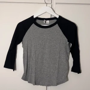 Grå och svart trekvarts tröja från H&M - En basic långärmad tröja från H&M i grått med svarta ärmar och krage.