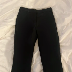 Svarta kostymbyxor från H&M, stl 34 - Klassiska svarta kostymbyxor från H&M i storlek 34. Byxorna har raka ben, ganska låga i midjan. Byxorna är små i storlek. 
