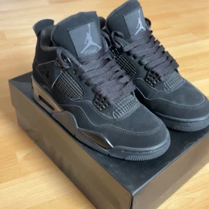 Svarta Nike Jordan 4 sneakers - Säljer ett par svarta Nike Jordan 4 sneakers med snyggt mesh på sidorna, ikonisk Jumpman-logga på plösen och platt sula. Skorna har snörning och är tillverkade i mocka och syntetmaterial. Perfekt för dig som vill ha en clean och stilren look. Priset kan diskuteras👍
