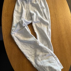 Ljusgrå mjukisbyxor från Divided XXS - Superbekväma ljusgrå mjukisbyxor från Divided i storlek XXS. Byxorna har dragsko i midjan och är gjorda i en mjuk bomullsblandning, perfekta för chill dagar. Klassisk passform med raka ben och enkel stil.