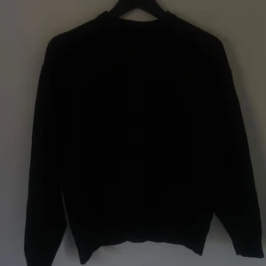 Svart stickad tröja från Zara - En klassisk svart stickad tröja från Zara i storlek S. Tröjan har rund halsringning, ribbade muddar och lång ärm. Perfekt för lager-på-lager och enkel att matcha med allt i garderoben.